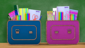 Back to school. Two vintage backpacks full of school supplies for boys and girls into a classroom.